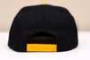 Broome Dusters™ Hat (Snapback) in black with yellow adjustable snap closure and structured high-profile design