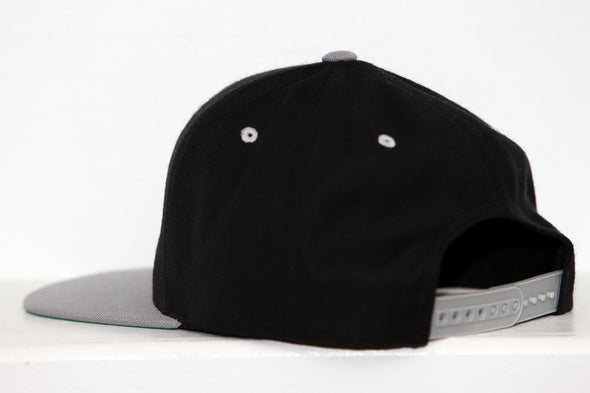 Black and gray New Haven Nighthawks snapback hat viewed from the back with adjustable strap visible